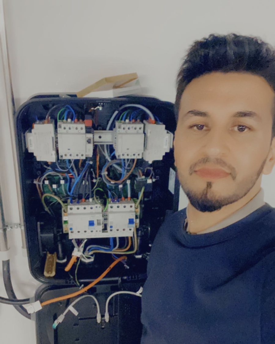 Elektriker von Zaheen Elektrotechnik vor einer offenen Steuerung mit Schützen und Sicherungsautomaten
